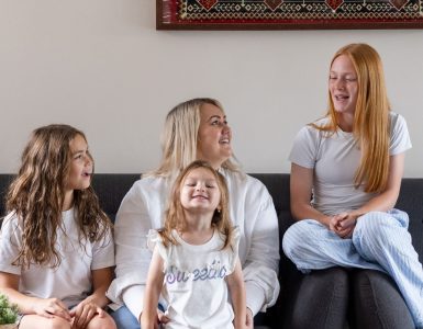 A woman and her three children smiling and laughing on a sofa